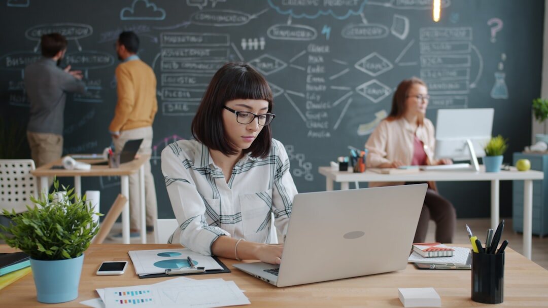 Young entrepreneurs working in modern startup office with whiteboards and laptops